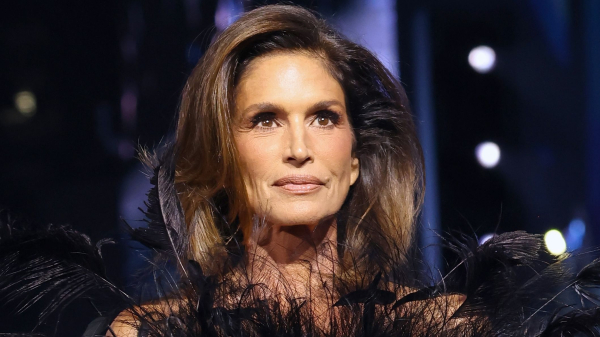 Cindy Crawford walking in a Gucci fashion show in a black feathered dress
